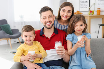 Happy family with glasses of milk in living room