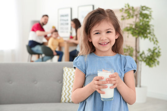 Cute little girl with glass of milk at home