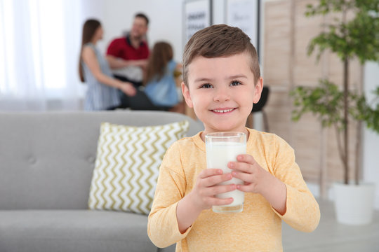 Cute little boy with glass of milk at home