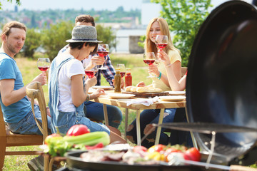 Young people having barbecue with modern grill outdoors