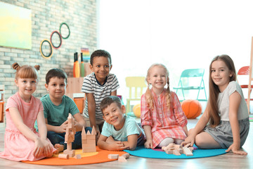 Cute little children playing with wooden blocks indoors