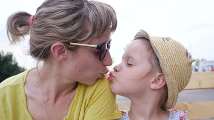 Young mother and child girl daughter tenderly kiss each other cheeks and lips portrait outdoors - Powered by Adobe