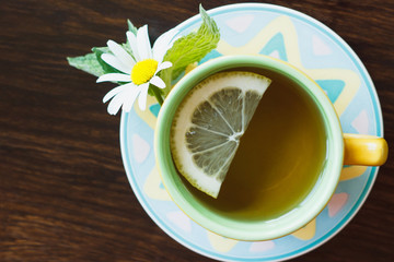 Cup of herbal tea with chamomile and lemon on the wooden background