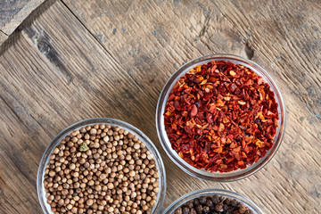 Glass bowls with various spicies on wooden barrel, top view, close-up, selective focus.