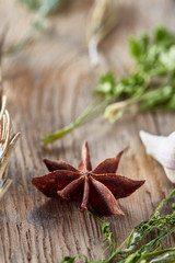 Anise star, parsley and other greenery on wooden background, close-up, shallow depth of field, vertical.