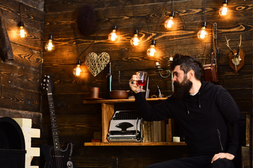 Relaxing evening. Man with beard holds glass of mulled wine hot seasonal beverage. Guy in cozy warm atmosphere drinking. Man bearded enjoy evening with warming beverage, wooden background