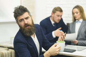 Business partners or businessman at meeting, office background. Negotiations concept. Man with beard drinks tea while waiting for bosses decision. Business negotiations, discuss conditions of deal