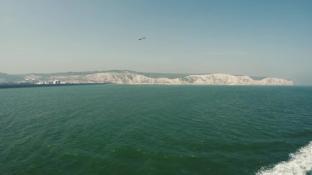 Dover Cliffs filmed from the ferry with gulls flying behind the boat