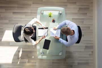 Elevated View Of Two Businesspeople Holding Resume