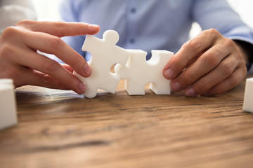 Two Businesspeople Connecting Jigsaw Pieces