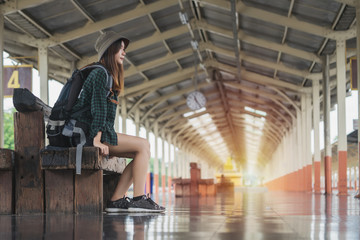 Traveler woman sitting and waits train on railway platform