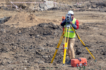 The surveyor is shooting at a building site - obrazy, fototapety, plakaty