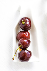 Red cherries on a white spoon and white background.