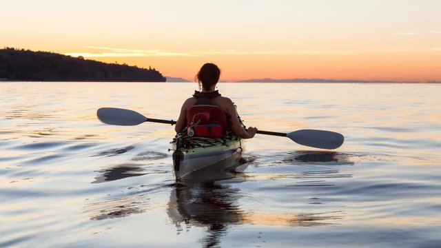 Cinemagraph of a woman enjoying the beautiful ocean scenery on a sea kayak during a vibrant sunset. Taken near Jericho Beach, Vancouver, British Columbia, Canada. Still image continuous loop animation