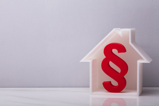 Close-up Of Red Paragraph Symbol Inside House Model