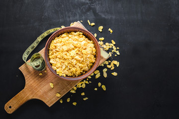Plate with cornflakes on black background