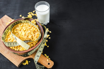 Plate with cornflakes on black background