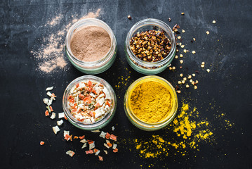 Different kinds of spices in glass and food ingredients on black. Copy space
