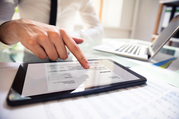 Businessperson Analyzing Invoice On Digital Tablet - obrazy, fototapety, plakaty