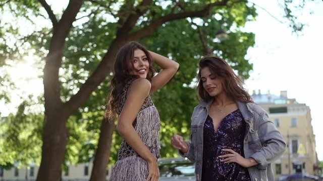 Two young woman posing near luxury sports car in a city