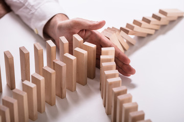 Businessperson Stopping Wooden Blocks From Falling