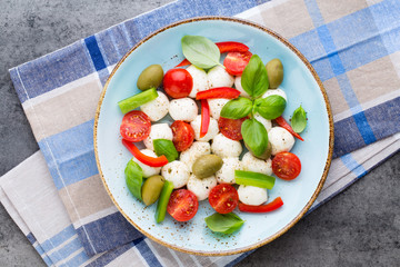Delicious caprese salad with ripe cherry tomatoes and mini mozzarella cheese balls with fresh basil leaves.