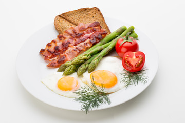 Fried eggs with bacon on the wooden table.