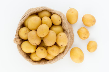 Sack of fresh raw potatoes on wooden background, top view