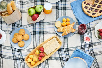 Top view of tasty food on tablecloth - fresh fruits, pastry, jam and crispy bread
