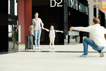 Happy little girl running to her father meeting his family in airport lounge on arrival