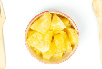 Pineapple in bowl on white background.