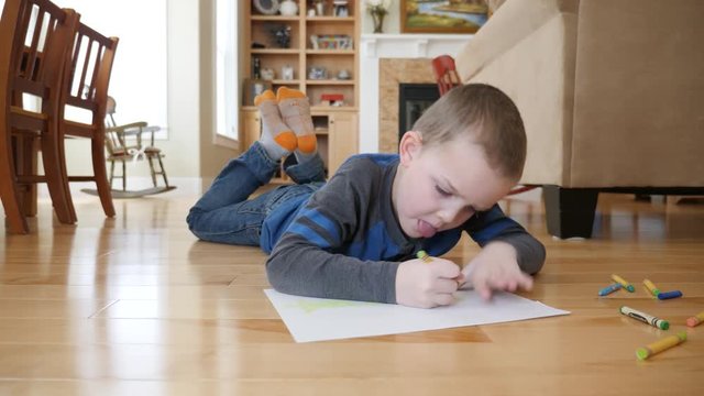 Dolly shot of a cute little toddler coloring on the floor