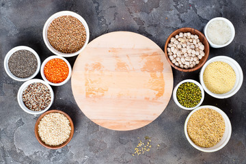 Superfoods and cereals selection in bowls with wooden board for your text on grey concrete background