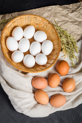 Chicken eggs in the basket on black wooden background. Copy space
