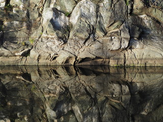 ancient rocks reflected in water along the Potomac river at sunset