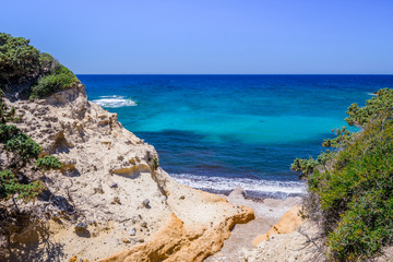 Beach, Greece - Kos Island, Kefalos: Picturesque deep blue Caribbean Bay with wild sea of ​​Greek Agais and steep sandstone cliffs, perfect for wind surfers with heavy waves