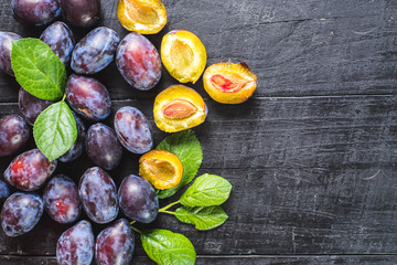 Many fresh plums on black background. Copy space