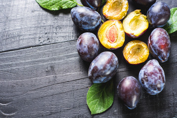 Many fresh plums on black background. Copy space