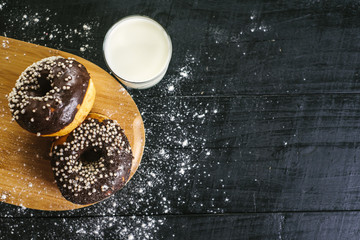 Sweet donats with glass of milk on black background. Copy space