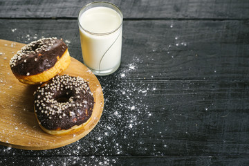 Sweet donats with glass of milk on black background. Copy space