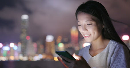 Young woman working on mobile phone at night