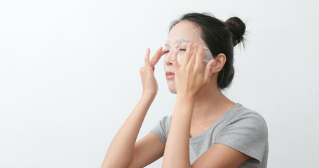 Fototapeta premium Woman apply paper mask and massaging on face