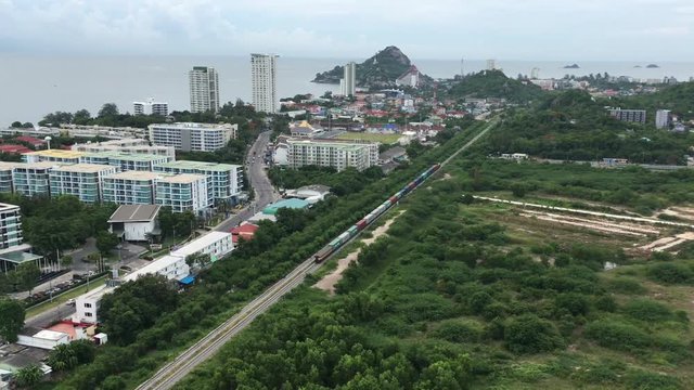 Footage video  Aerial view clip of long freight train passes through Hua Hin famous resort town in southern Thailand.