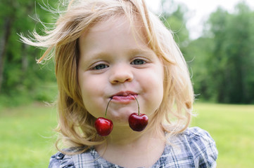 little girl with a sweet cherry in her mouth