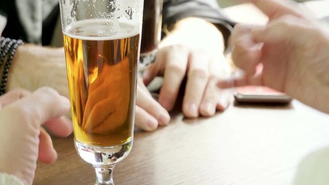 Close-up shot of male hands with glasses of beer in the restaurant. 4K