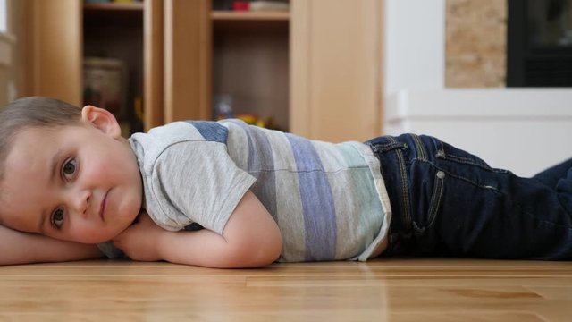 Dolly shot of little boy lying on the floor in a house