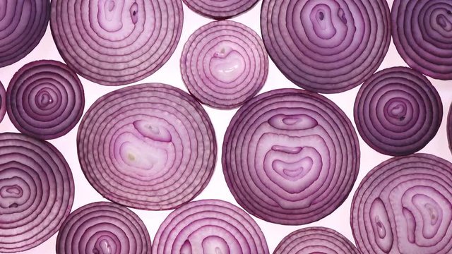Sliced red onion rings rotating on white in 4K. Closeup flat-lay view of healthy food background with vegetable of rich vitamin.
