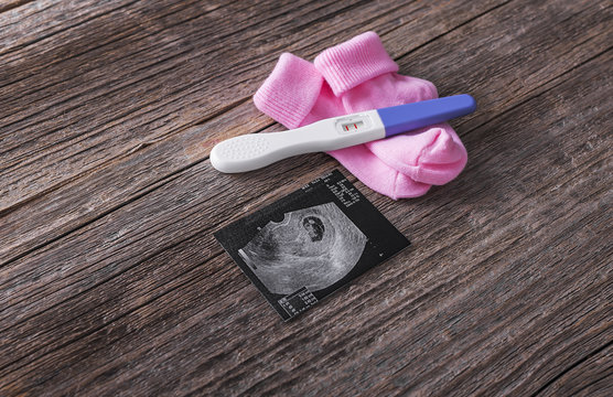 Pregnancy test and baby socks picture of the embryo.