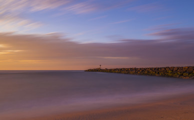 Dramatic sunrise viewed from Manasquan Beach, New Jersey shot using long exposure featuring sand in the foreground and moody sky on the background
