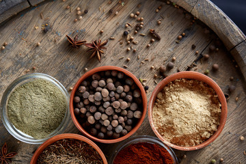 Spices in ceramic bowls on the top of wooden barrel, close-up, selective focus, vertical.